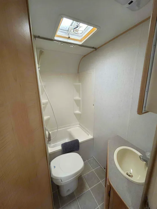 Clean, compact RV rental bathroom: features a white toilet, shower/tub, and vanity sink on grey tiled floor.. R-Vision Trail-Lite Trail-Cruiser 2004