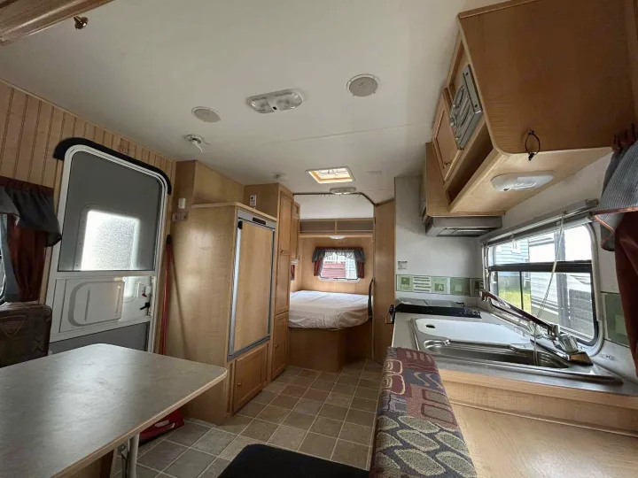 Inside this RV rental: a kitchen with sink/stove, dining table, fridge, and cozy rear bedroom.. R-Vision Trail-Lite Trail-Cruiser 2004