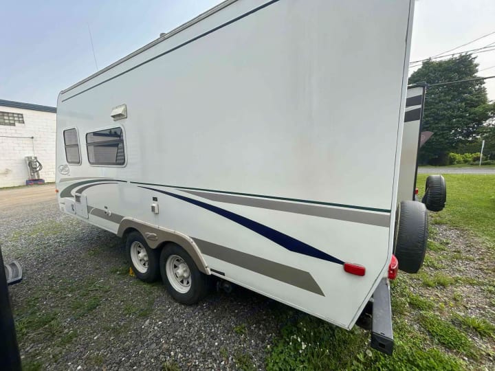White RV rental parked on gravel, featuring blue/grey graphics & rear spare tire. Perfect for outdoor adventures.. R-Vision Trail-Lite Trail-Cruiser 2004