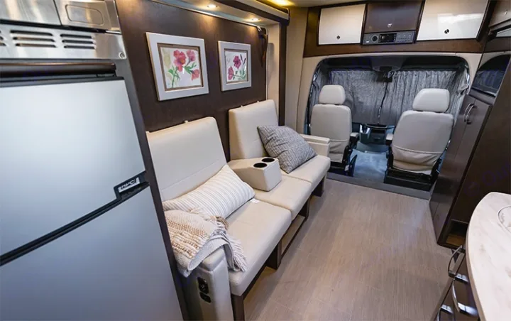 This RV rental features a cozy interior with a refrigerator, plush seating, wall art, and the forward cab area.. Leisure Travel Vans Unity 2016