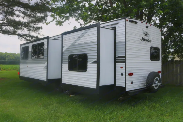Jayco RV rental: White travel trailer with extended slide-outs, parked in a lush, green setting.. 1UJBC0BT8S1YT0519 321BDS 2025