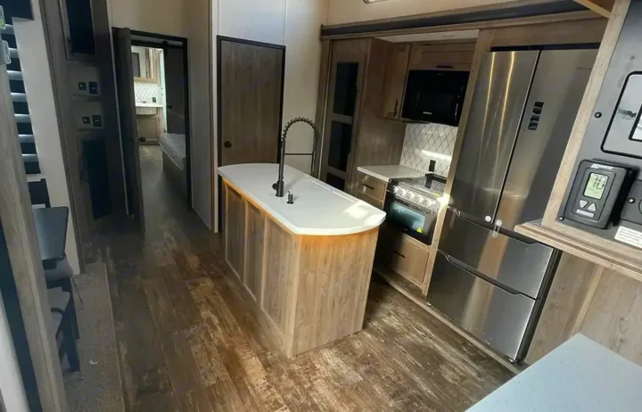 Spacious modern RV rental interior with a fully equipped kitchen, island, stainless appliances, and hallway.. Forest River Sabre 2021