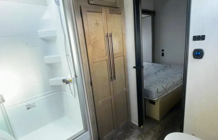 Inside this RV rental, see the efficient shower/tub, central storage cabinet, and glimpse of the comfortable bedroom.. Forest River Sabre 2021