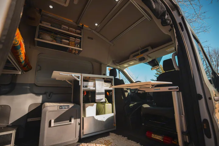 Inside a modern RV rental camper van: compact kitchen, Lagun table, fridge, and overhead storage.. Vandoit LIV 2019