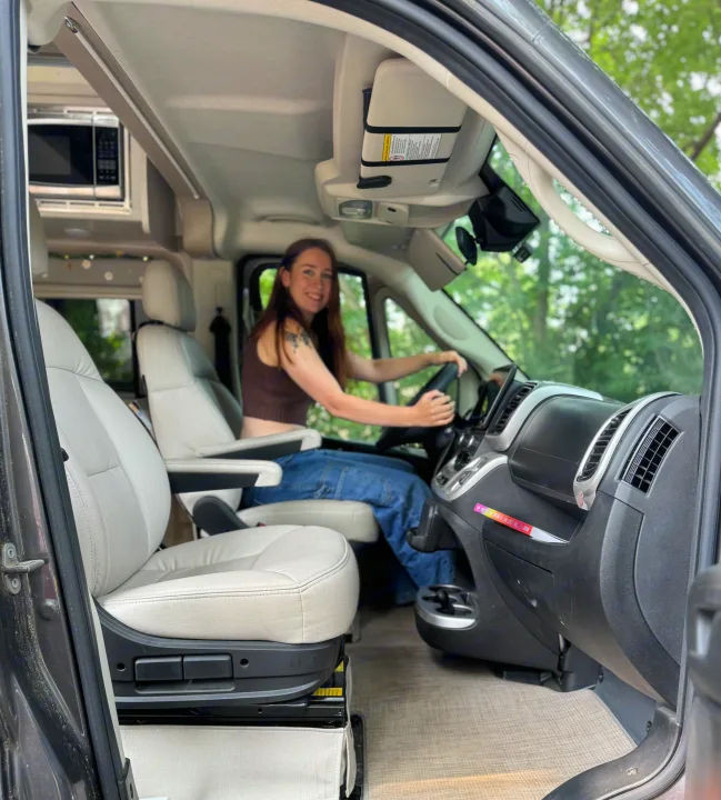 This RV rental's cozy interior features a smiling woman in the driver's seat, ready for a road trip adventure.. Thor Motor Coach 18A Rize 2023