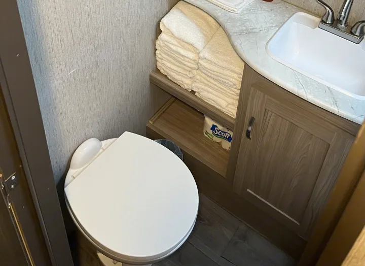 RV rental bathroom features toilet, sink, vanity with stacked towels & toilet paper. Compact and functional.. Coachmen Freedom Express Ultra Lite 292BHDS 2021