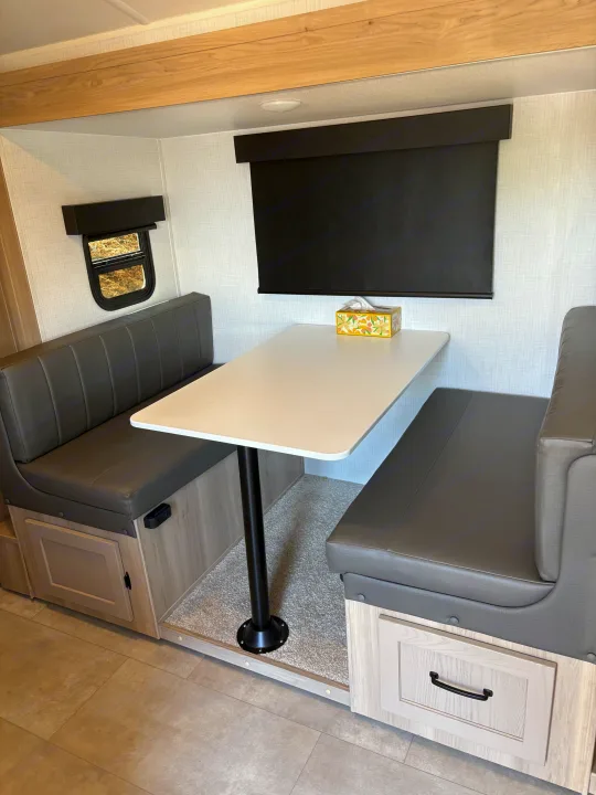 RV rental dinette: gray benches, white table, and storage. A cozy space for meals or relaxing inside your camper.. FlagStaff E-PRO 20BH 2025