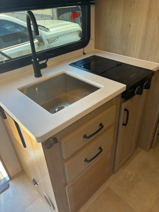 Clean RV rental kitchen interior, featuring a modern sink, black faucet, and two-burner Greystone stovetop.. FlagStaff E-PRO 20BH 2025