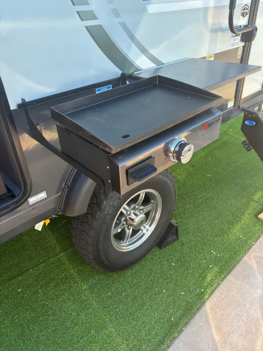 This RV rental features an outdoor Suburban griddle attached, great for campground cooking. Parked on artificial turf.. FlagStaff E-PRO 20BH 2025