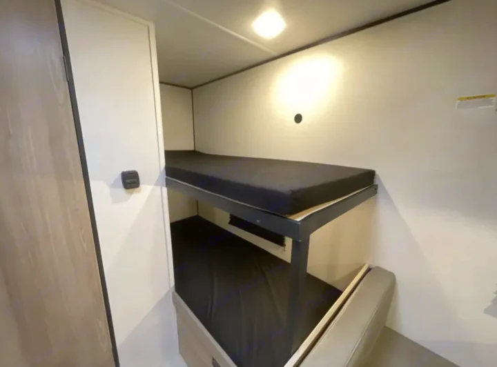 RV rental interior: cozy bunk beds with black mattresses & bright light. Perfect for travel accommodations.. Other Other 2025