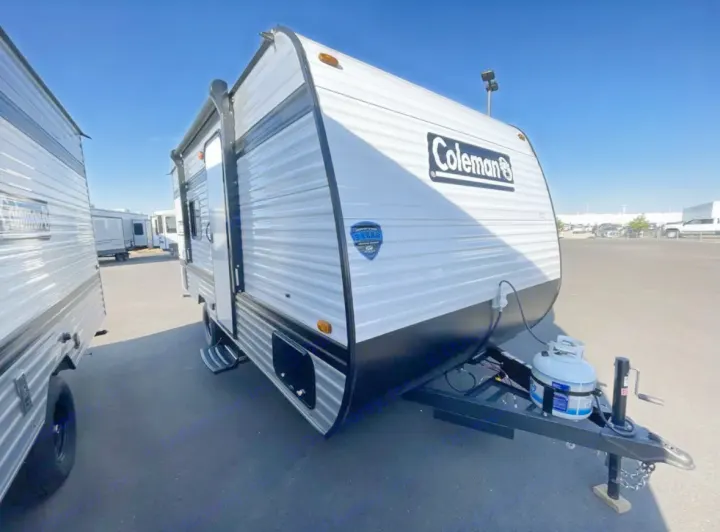 This white and black Coleman travel trailer RV, ideal for an RV rental, is shown parked outdoors with a visible propane tank.. Other Other 2025
