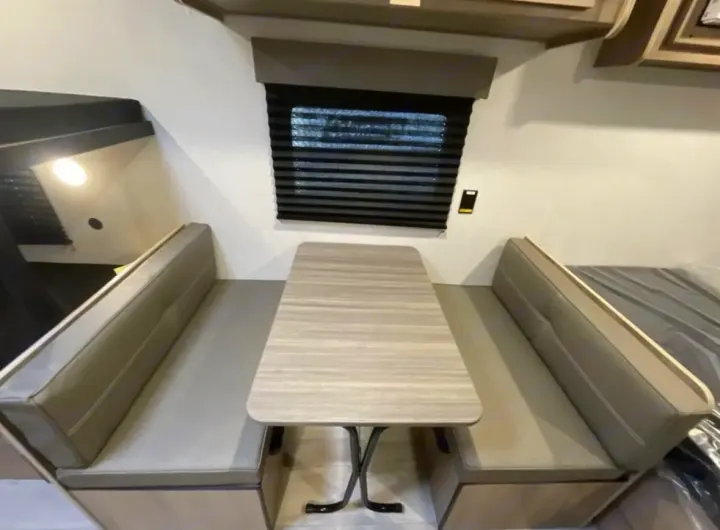 RV rental dinette showing a table, benches, and window with blinds, creating a cozy and functional living space.. Other Other 2025