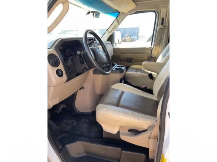 RV rental interior: The driver's cabin features tan and brown seats, dashboard, and steering wheel for comfortable travel.. Coachmen Leprechaun 2019