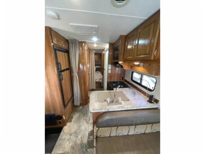Spacious RV rental interior with full kitchen, dining area, and bedroom beyond. Perfect for travel adventures.. Coachmen Leprechaun 2019