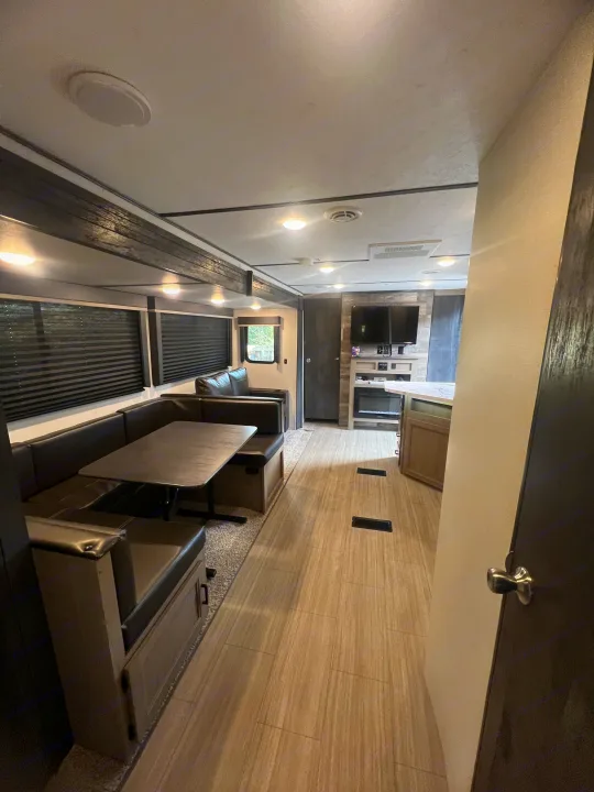 Inside an RV rental: a modern living space featuring a U-shaped dinette, entertainment center, and kitchen island.. Keystone RV Hideout 2021