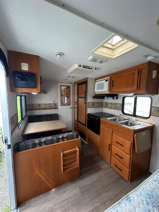 Clean RV rental interior with a kitchen, dinette, and entertainment system, perfect for road trip adventures.. Terry Dakota 722F 2004