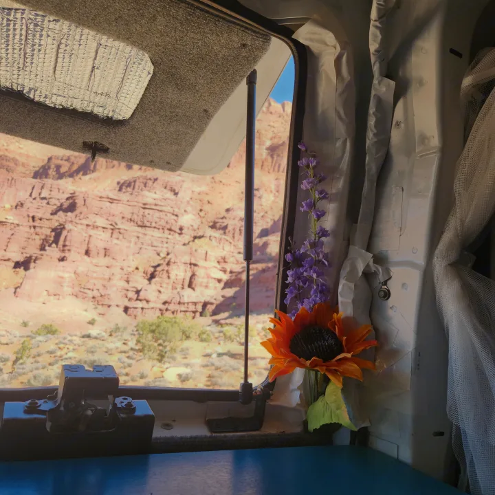 Scenic desert views from inside an RV rental. A window opens to red rock formations; flowers adorn the cozy interior.. Chevrolet Express 1500 AWD 2014