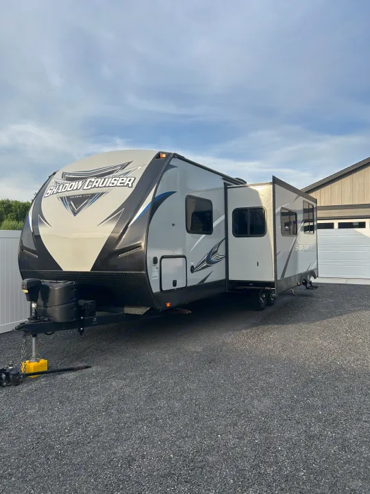 This sleek grey Shadow Cruiser travel trailer, a great RV rental option, is parked on a gravel drive with its slide-out extended.. Cruiser RV Shadow Cruiser 2018