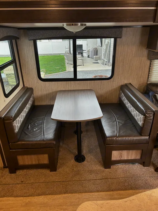 This RV rental features a comfortable dinette with brown faux leather benches and patterned backrests, ideal for dining.. Cruiser RV Shadow Cruiser 2018