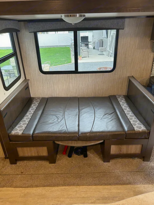 This inviting RV rental dinette features dark leatherette benches, patterned backrests, and scenic windows.. Cruiser RV Shadow Cruiser 2018