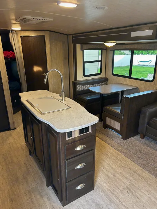 Inside this RV rental: Features a well-equipped kitchen island, comfortable dining booth, and lounging area for travelers.. Cruiser RV Shadow Cruiser 2018