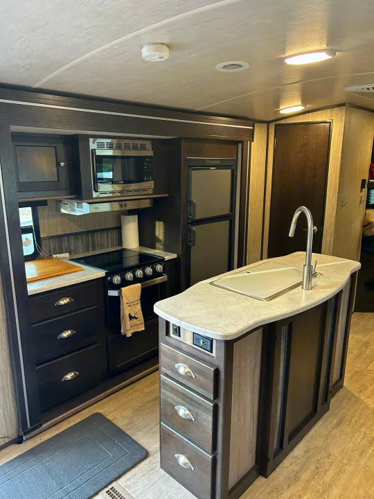 Fully equipped RV rental kitchen with sleek cabinets, island sink, stove, microwave, and refrigerator.. Cruiser RV Shadow Cruiser 2018