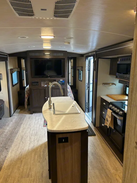 Spacious, modern RV rental interior with kitchen island, TV, and full amenities for comfortable travel.. Cruiser RV Shadow Cruiser 2018