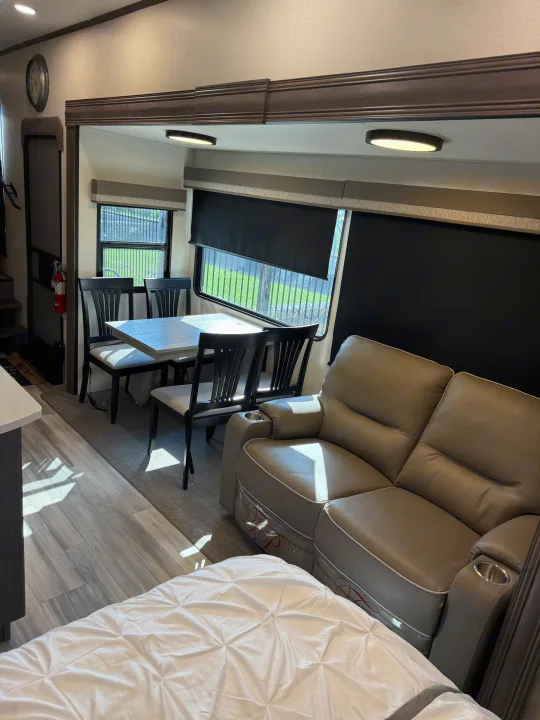 Step into this modern RV rental's interior: sunlit dining, comfy recliners, and a cozy bed.. Forest River 3370RLS 2024