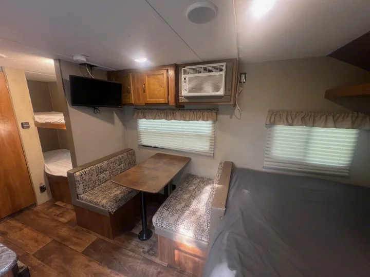 RV rental interior: A cozy dinette, bunk beds, kitchen space, and bed provide comfort for your travel adventures.. Keystone RV Summerland Mini 2017