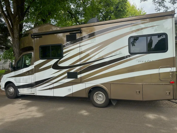 This sleek brown & white Tiffin Wayfarer RV rental is a premium motorhome parked under lush trees.. Wayfarer Wayfarer Motorhome 2018