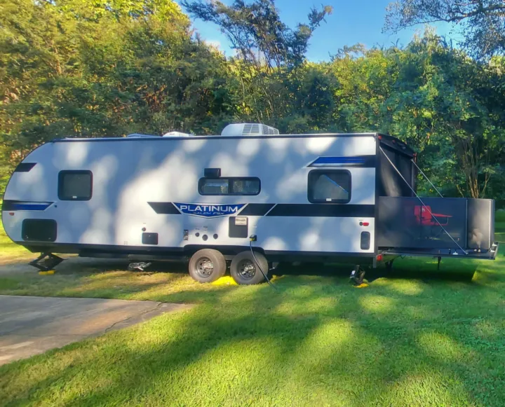 Sunny RV rental at a green campground! This grey travel trailer with a rear patio offers outdoor enjoyment.. Forest River Salem 2022