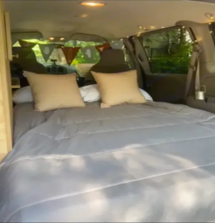 Cozy RV rental interior: comfy bed, pillows, string lights, & festive bunting. Ready for travel!. Dodge Caravan 2006