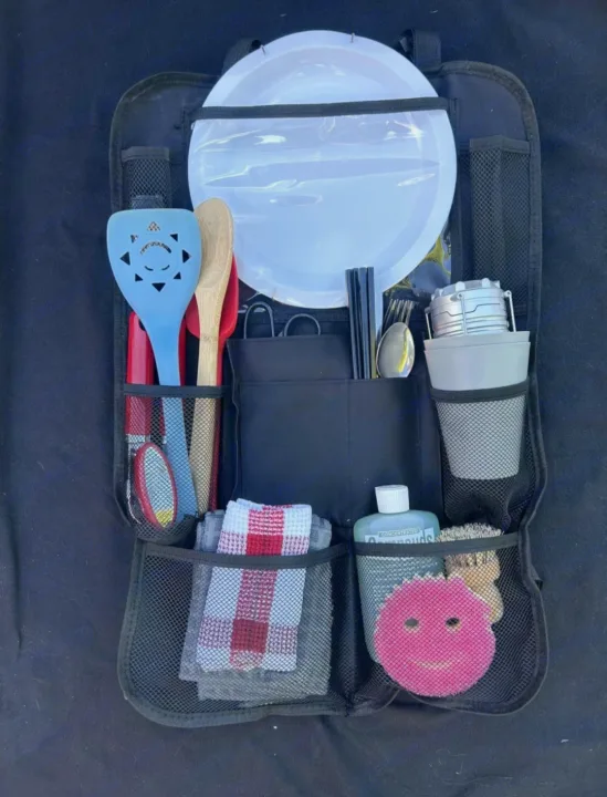RV rental kitchen organizer packed with plates, utensils, and cleaning supplies for camping trips.. Dodge Caravan 2006
