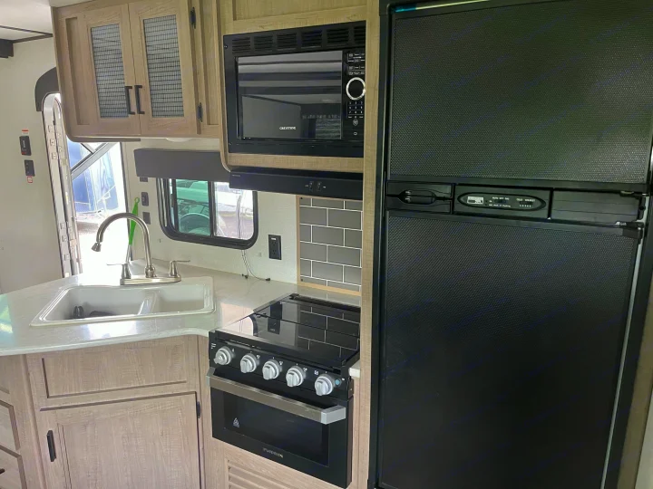 This rv rental features a modern kitchen with a sink, stove, microwave, and refrigerator, perfect for travel trailer adventures.. Keystone RV Hideout LHS 2020