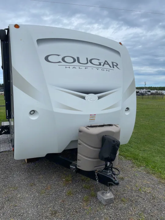 Close-up of a white travel trailer's front, labeled "Cougar Half-Ton," perfect for an rv rental.. Keystone RV Cougar 2018