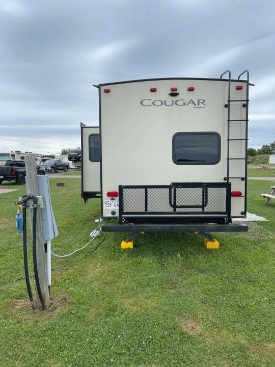 Cougar travel trailer rv rental, set up at a scenic campsite with utilities. Perfect for your next New Brunswick adventure.. Keystone RV Cougar 2018
