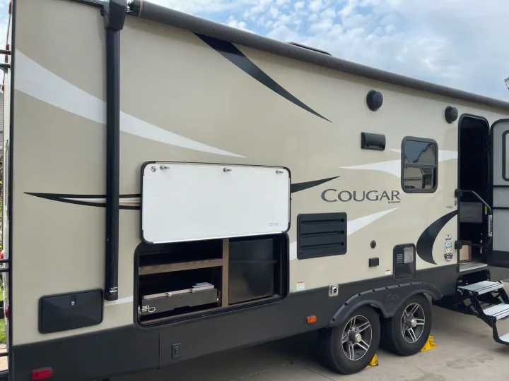 Side view of a modern Cougar RV, perfect for rv rental, featuring an outdoor kitchen and ample storage.. Keystone RV Cougar 2018