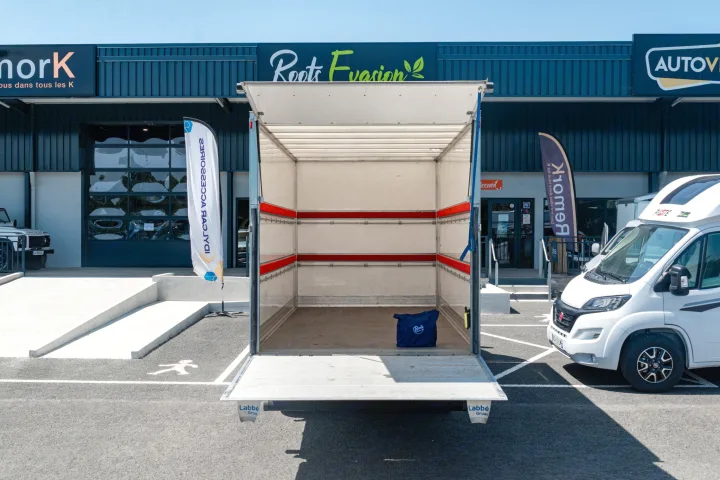 View into an open moving truck, with a white RV next to it, at a "Roots Evasion" facility for rv rental.. IVECO 35C16 2023