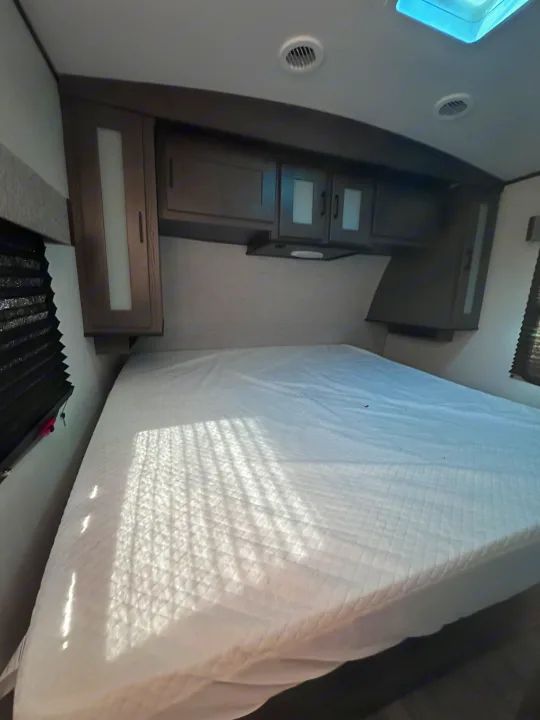 Inside an RV rental: Compact bedroom featuring a large bed, overhead storage, and sunlit window blinds.. MPG Cruiser RV ultra light 2500 2021