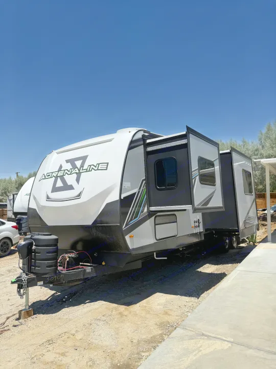Adrenaline toy hauler travel trailer for RV rental, showing extended slide-outs parked on a sunny day.. Coachmen Adrenaline 2025