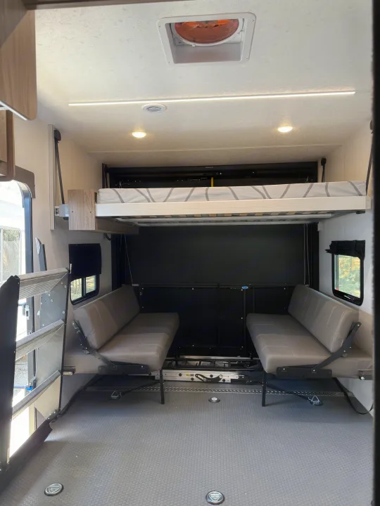 RV rental: Multipurpose toy hauler interior with electric bunk bed, two convertible sofas, and durable floor.. Coachmen Adrenaline 2025