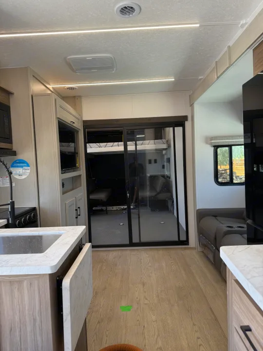 Spacious RV rental interior: kitchen, living area, & large rear garage with bunk, ideal for adventures.. Coachmen Adrenaline 2025