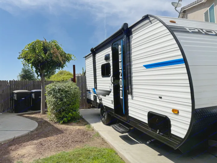 New Pioneer RV rental, a white & black travel trailer, parked on concrete. Ready for outdoor adventures.. Heartland Pioneer 2025