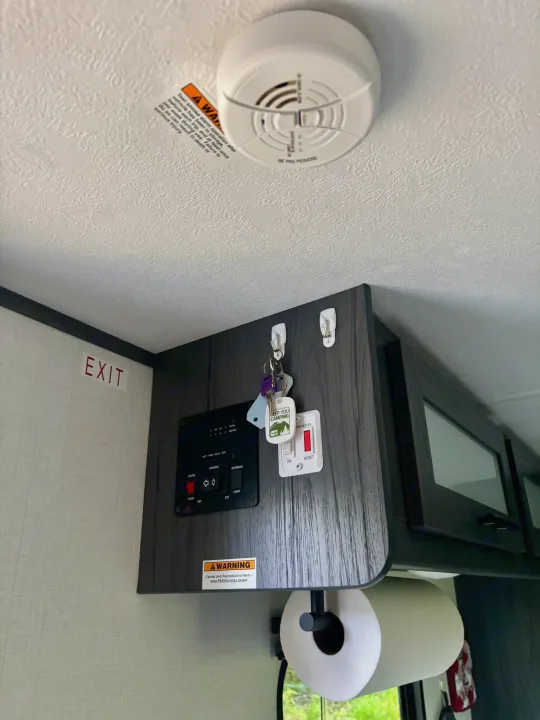 RV rental interior featuring a smoke alarm, essential control panel, keys, and water heater switch, ensuring a safe trip.. Dutchman Aspen Trail 2025