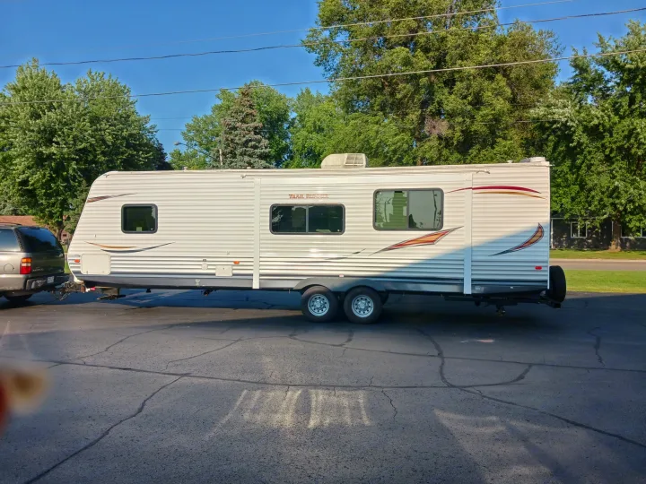 A sleek travel trailer is hitched to an SUV, ready for an RV rental getaway under a clear sky.. Heartland RVs Trail Runner 2013
