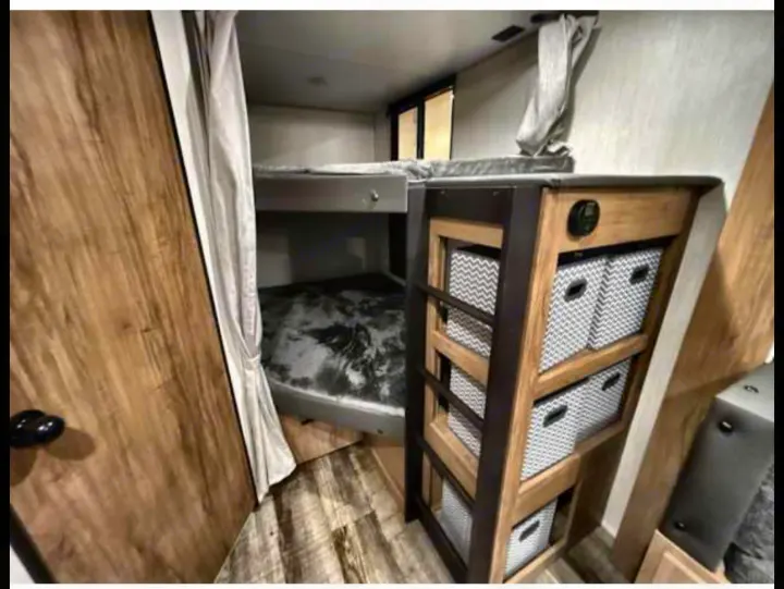 RV rental: Bunk beds, privacy curtain, and clever storage unit with patterned bins offer smart space solutions.. Forest River Campsite Reserve 26CJ 2025