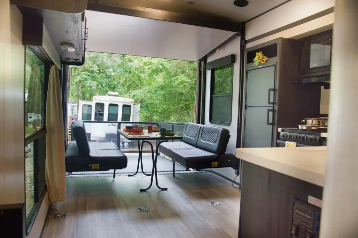 Spacious RV rental interior with an open patio, dining area, kitchen, and a beautiful nature view beyond.. Cruiser Stryker 2022