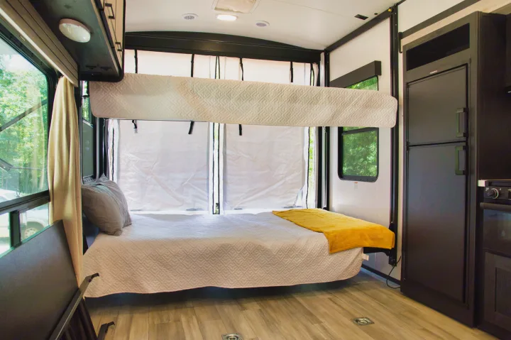 Spacious RV rental interior with bunk beds, a cozy main bed, and a compact kitchen. Perfect for family adventures!. Cruiser Stryker 2022