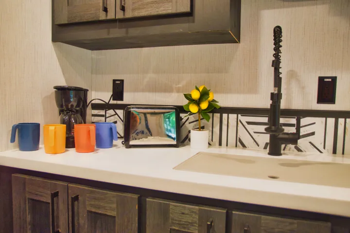 Stylish RV rental kitchen counter: coffee maker, toaster, colorful mugs, lemon decor, modern faucet, and sink with geometric backsplash.. Cruiser Stryker 2022