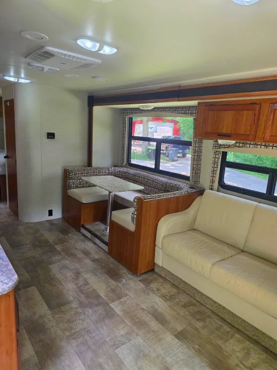 Explore this RV rental's spacious living area, featuring a comfortable dinette, inviting sofa, and wood-look flooring.. Jayco Redhawk 2017